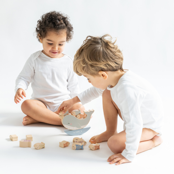 Two children playing with wooden toys on a white surface